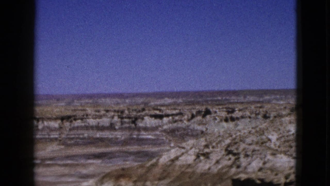 1953 Arizona 8mm view of dry flats and eroded pale rock formations framed by heavy black film edges.