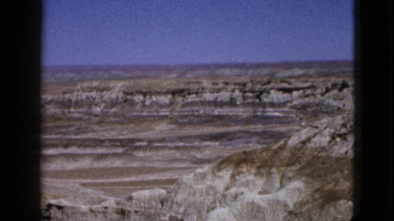 1953 Arizona 8mm frame showing pale layered desert rock and open blue sky from a distant overlook.