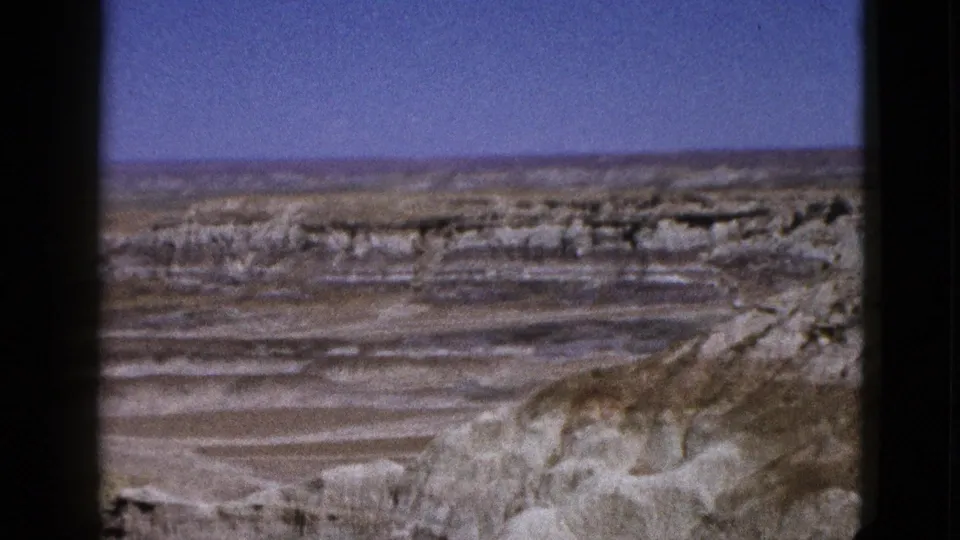 1953 Arizona 8mm frame showing pale layered desert rock and open blue sky from a distant overlook.