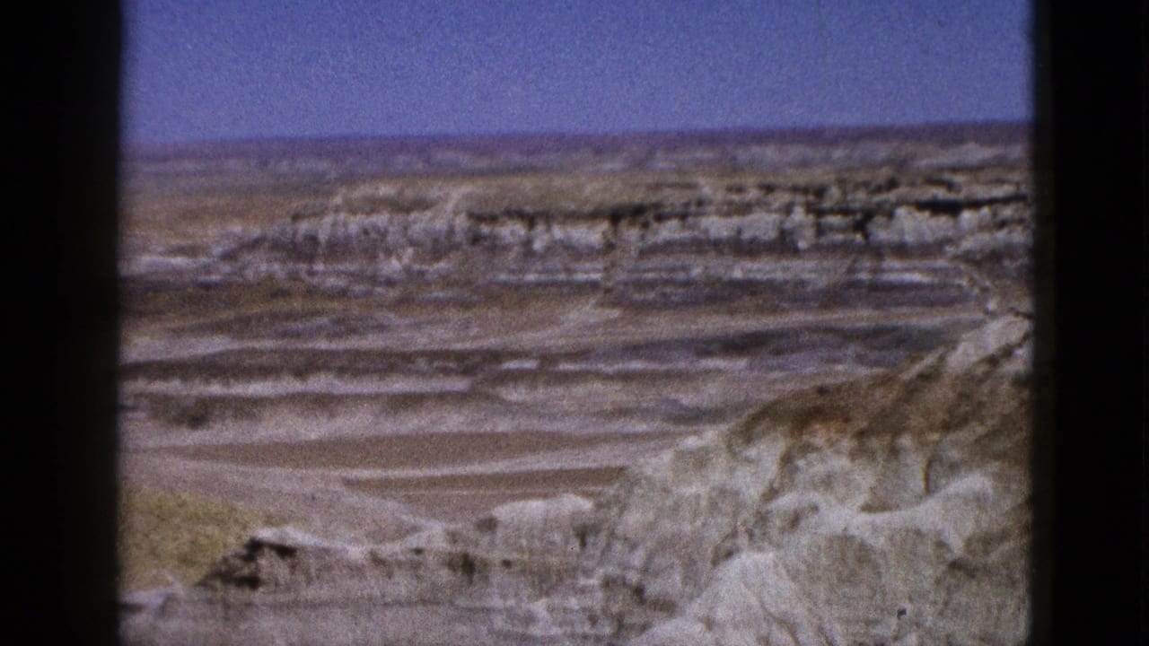 Wide arid landscape with pale cliffs and dark frame borders.