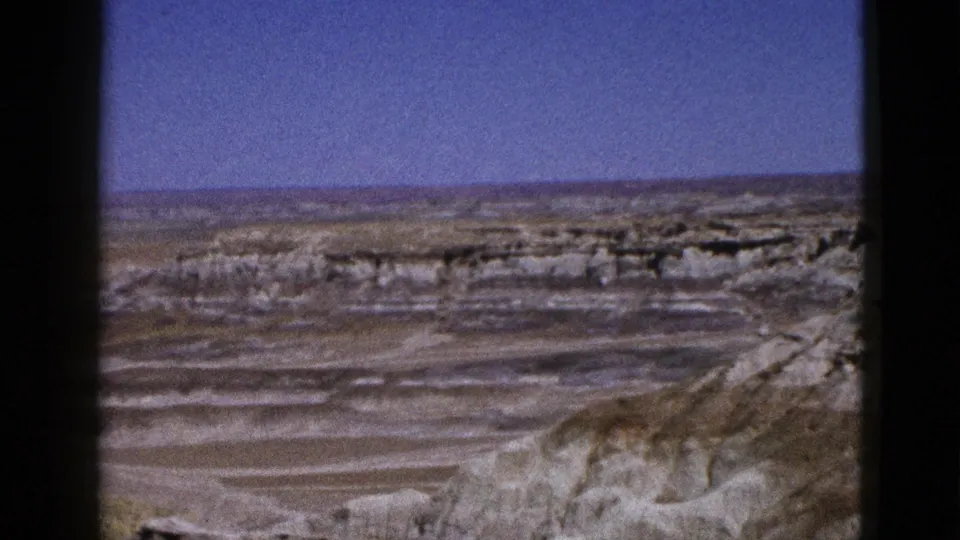 1953 Arizona home-movie frame showing a desolate rocky desert overlook with layered formations and clear sky.