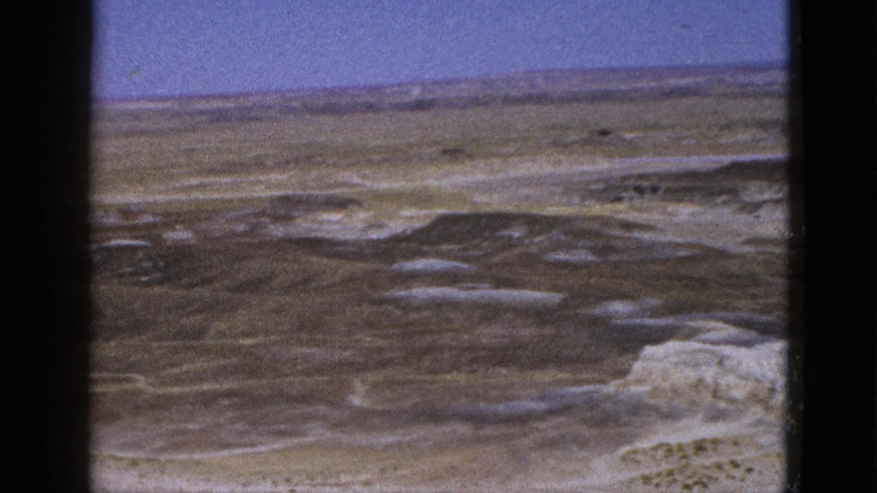 1953 Arizona 8mm frame showing an open arid plain, distant horizon, and blue sky through soft film grain.