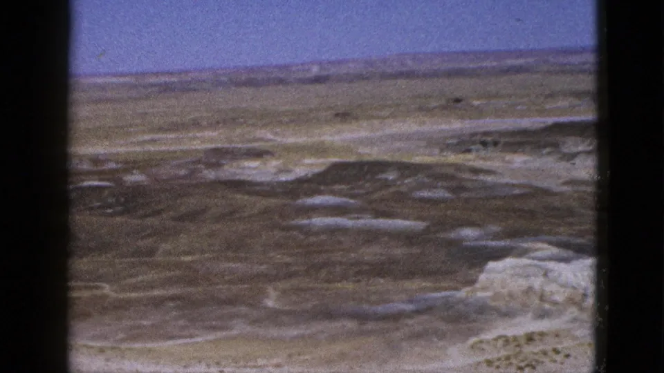1953 Arizona 8mm frame showing an open arid plain, distant horizon, and blue sky through soft film grain.