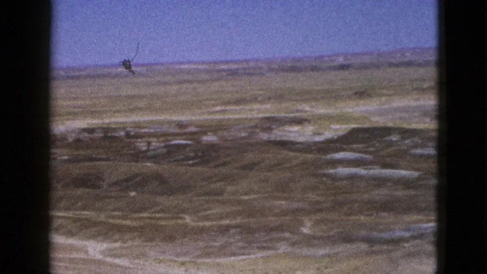 1953 Arizona home-movie frame of a dry desert plain with low vegetation, pale tracks, and visible film wear.