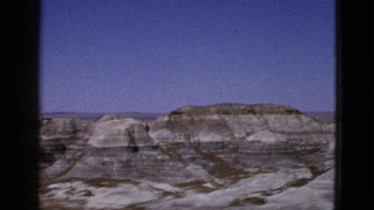 Layered desert hills and eroded rock formations under open sky.