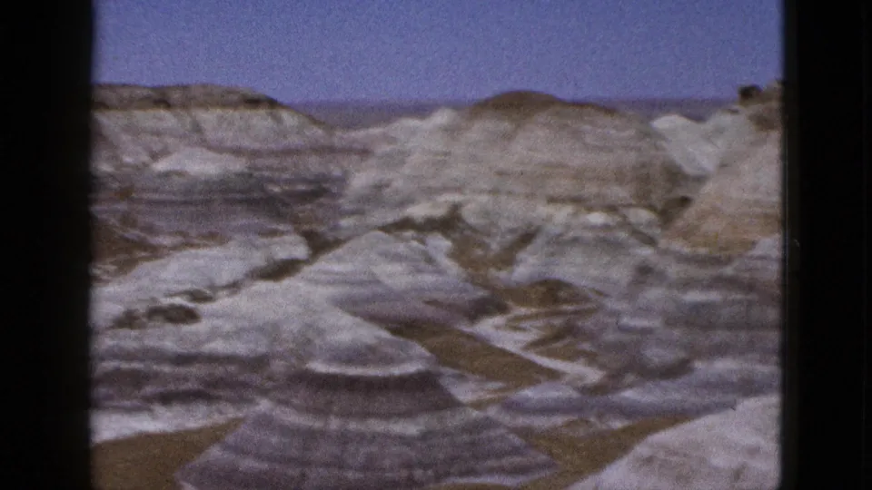 1953 Arizona travel footage frame with a rounded pale rock mound, layered hills, dry terrain, and soft 8mm color.