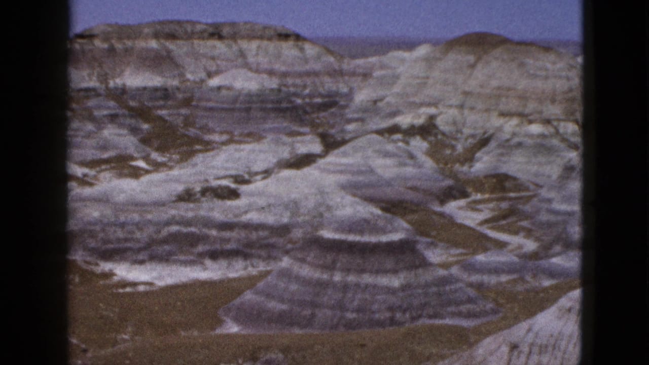 Layered desert rock formations beneath a blue sky.