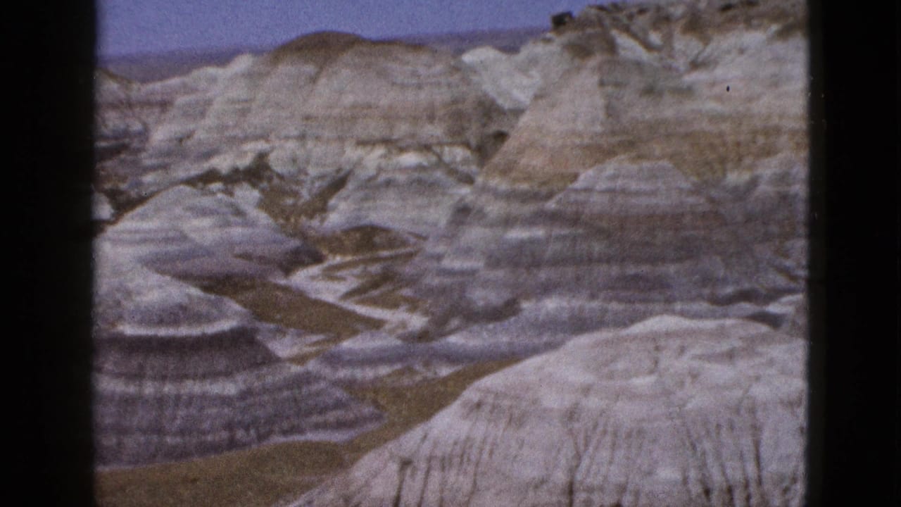 1953 Arizona home-movie view of striped sediment hills, shallow ravines, and a low rocky ridge.