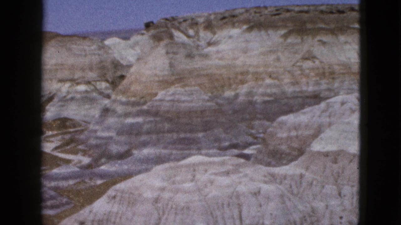 1953 Arizona home-movie view of pale striated desert hills and eroded cliffs under blue sky.