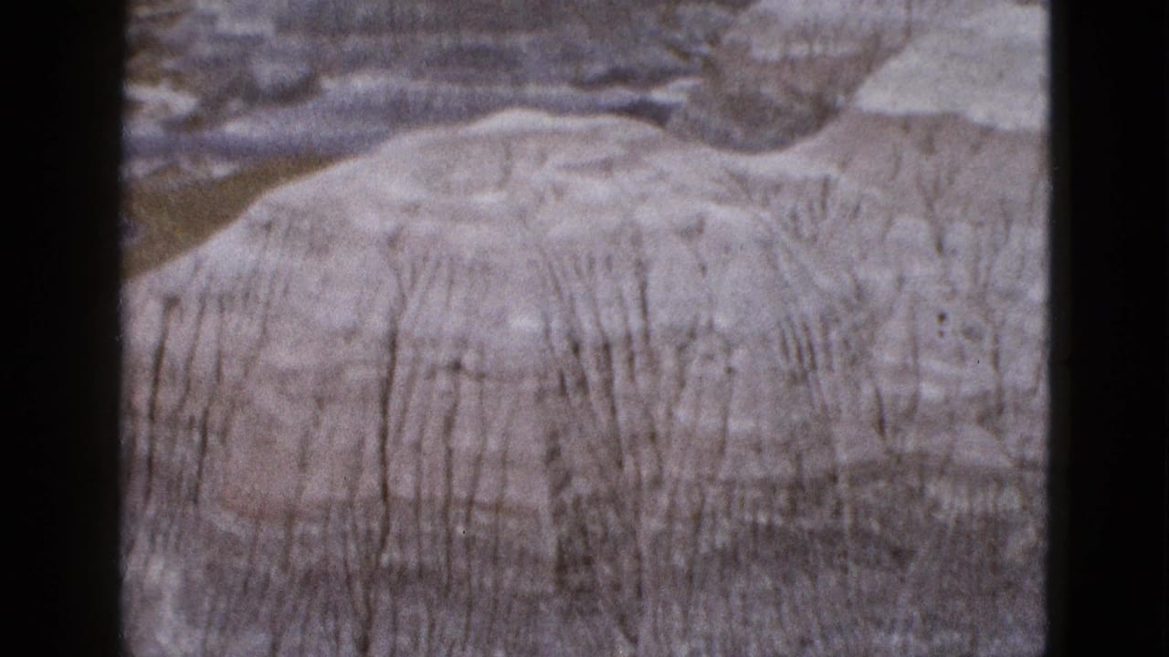 Close view of a pale rounded hill with vertical erosion lines.