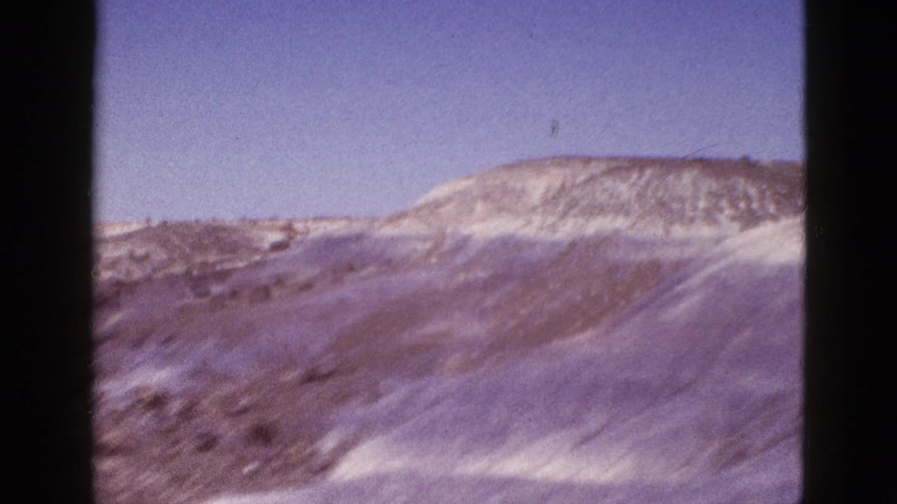 Low desert hills under a clear sky with a dark film-strip edge at left.