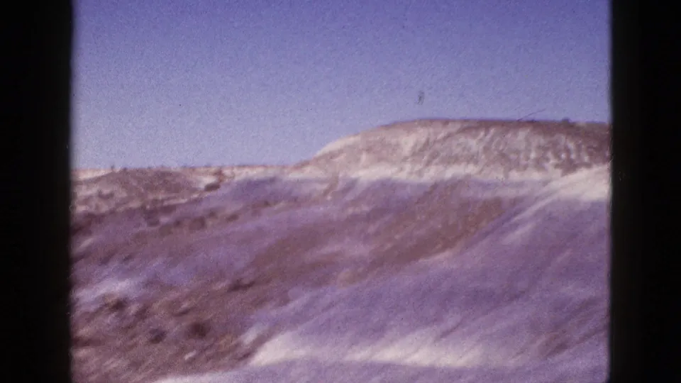 1953 Arizona 8mm frame showing pale desert hills and open sky, with the contact-sheet border visible.