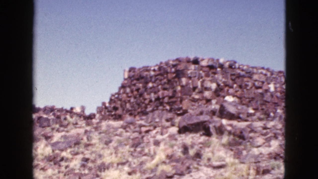 1953 Arizona 8mm frame showing a weathered stone ruin on a dry, rocky hill with sparse grass and open sky.