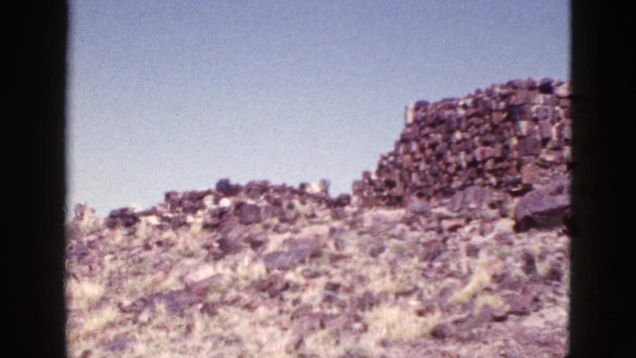 Stone ruin remains on a dry hilltop with rocks and brush below.