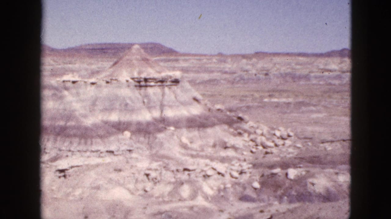 Pale desert canyon formations beneath a clear blue sky.