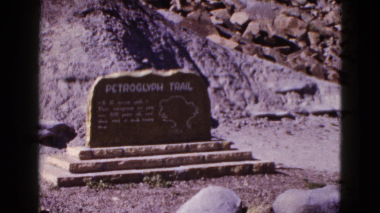 1953 Arizona 8mm frame showing a Petroglyph Trail sign with a map outline against a rocky hillside.