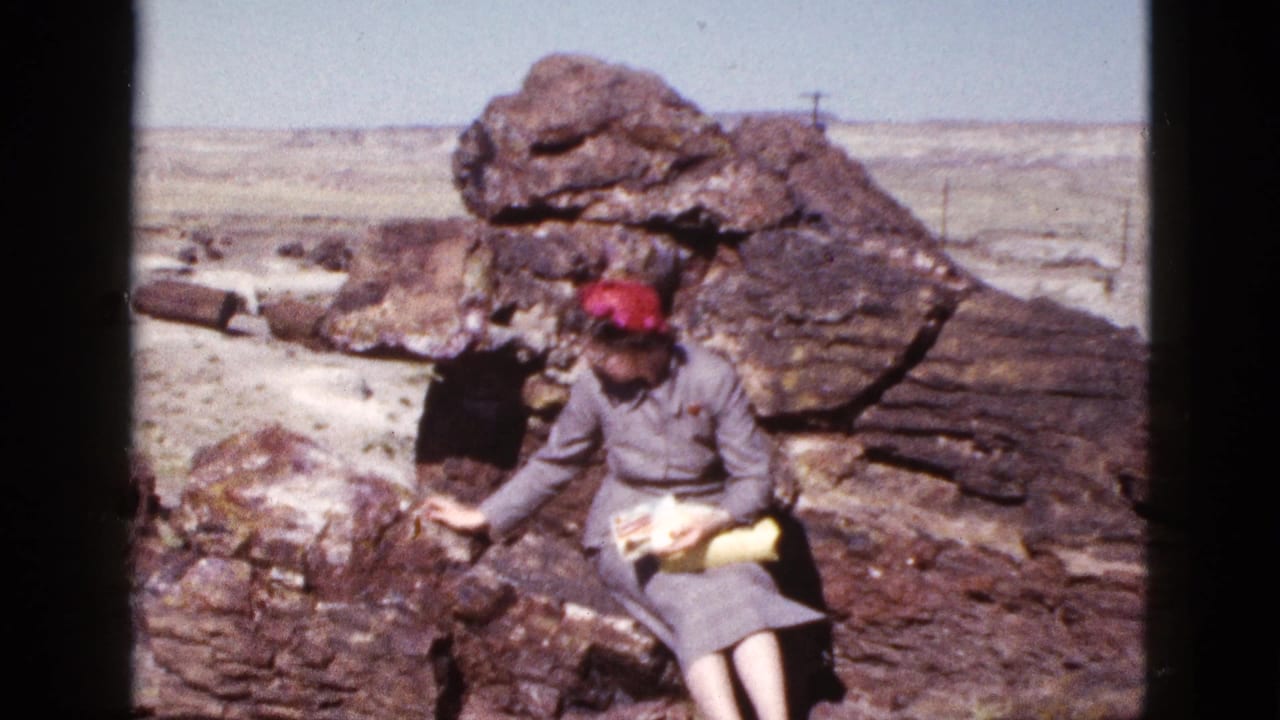 Woman looks down toward papers while seated beside a large rock formation.