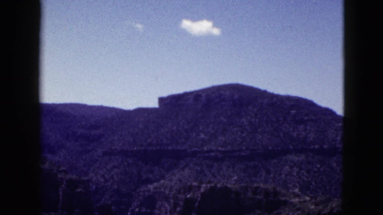 1953 Arizona home-movie frame showing a distant rocky mesa or mountain under blue sky, with no people visible in this still.