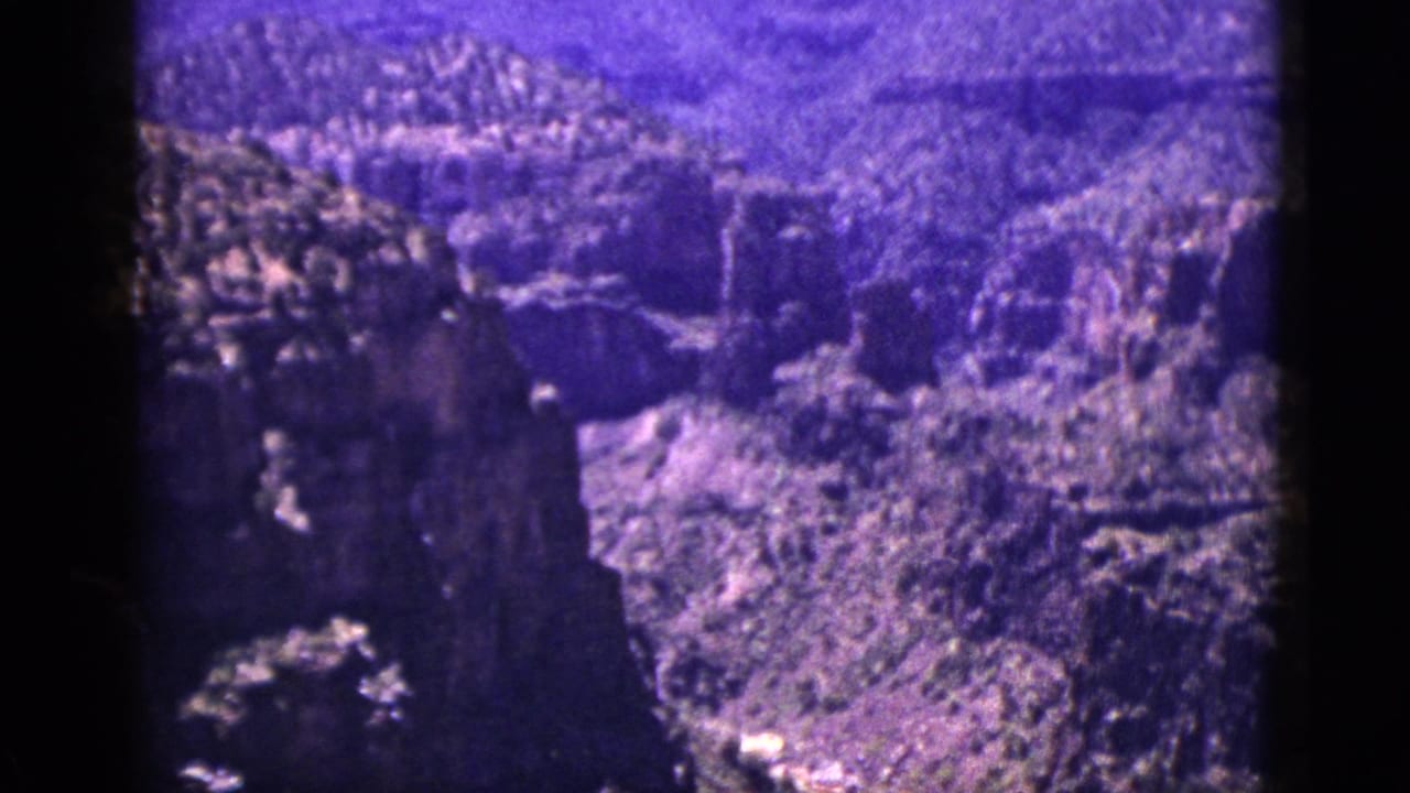 Rocky canyon landscape with a bright winding stream and dark film border.
