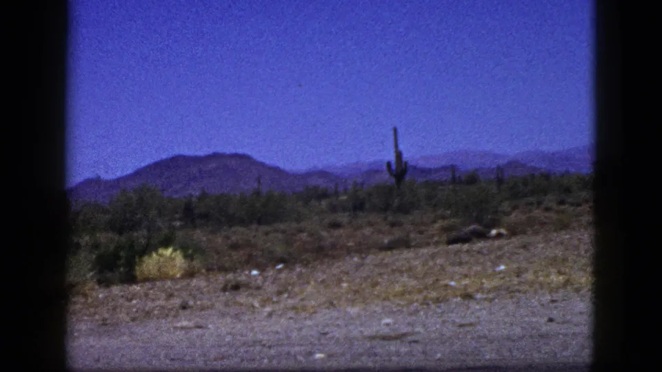 1953 Palm Desert 8mm view of cactus-dotted desert brush with a mountain ridge beyond and visible film-frame borders.