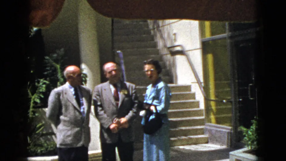 The 1953 Palm Springs scene shows three adults standing close together near exterior stairs and a planted wall.