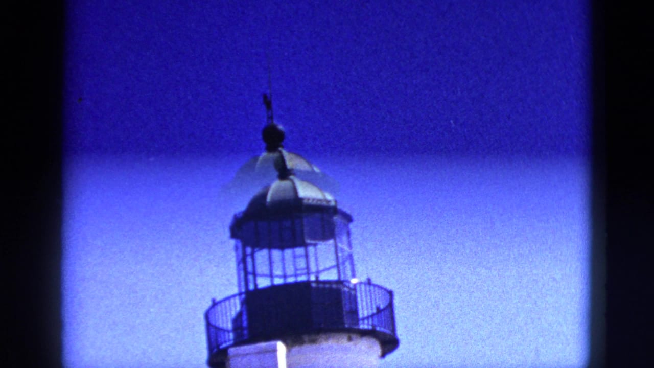 Lighthouse top with black lantern room, railing, and white tower below.