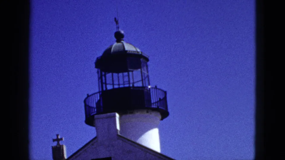 1953 California 8mm still showing a lighthouse-like tower rising above a building with a cross at the lower left.
