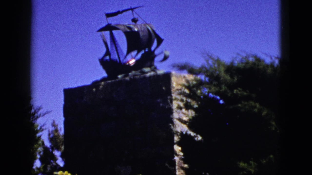 Ship-shaped monument on a stone pedestal against a deep blue sky.