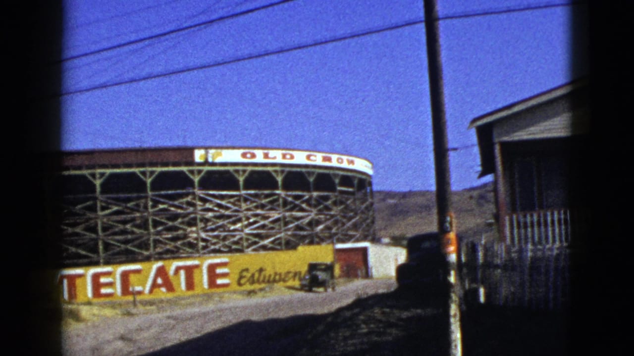 1953 California 8mm frame showing a circular building with Old Crow signage, a Tecate ad, utility lines, and a dirt roadside.