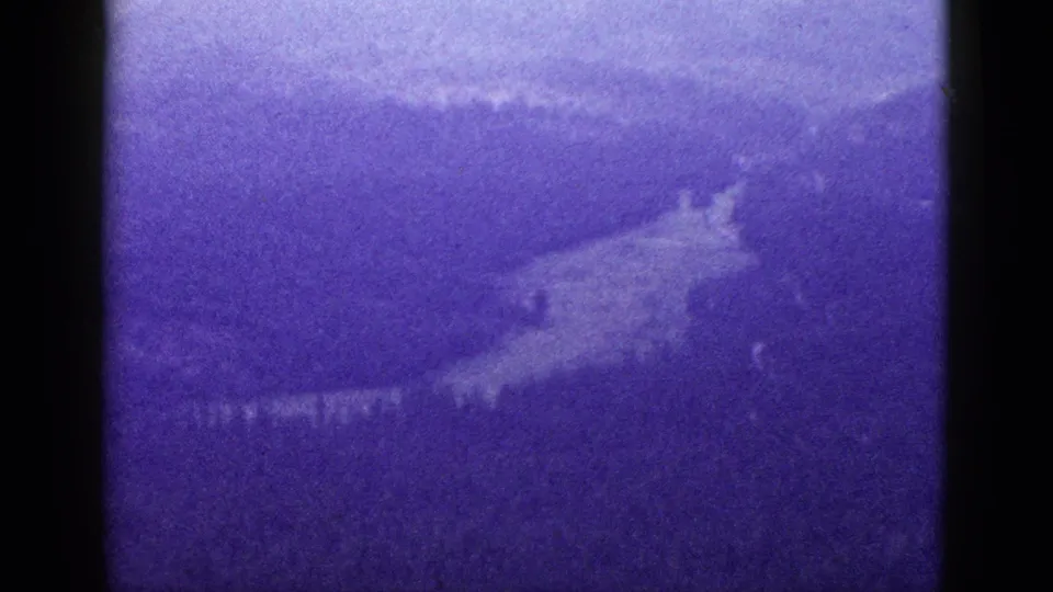 1953 California 8mm frame showing a hazy mountain valley and hillside under a purple-blue color shift.