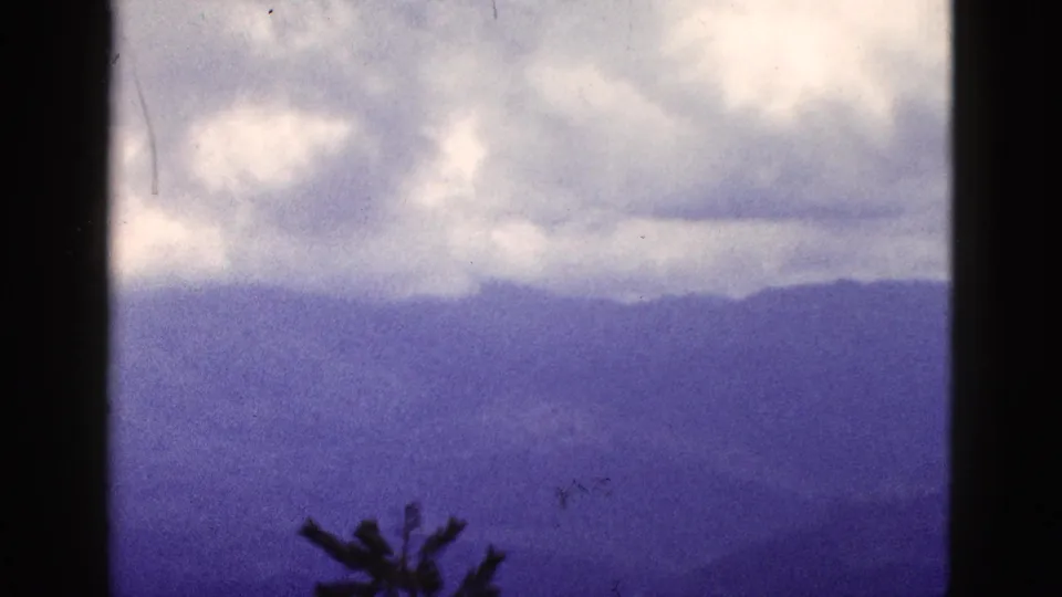 1953 California home-movie frame of fog and low cloud cover over layered mountain ridges, with visible 8mm frame edges.