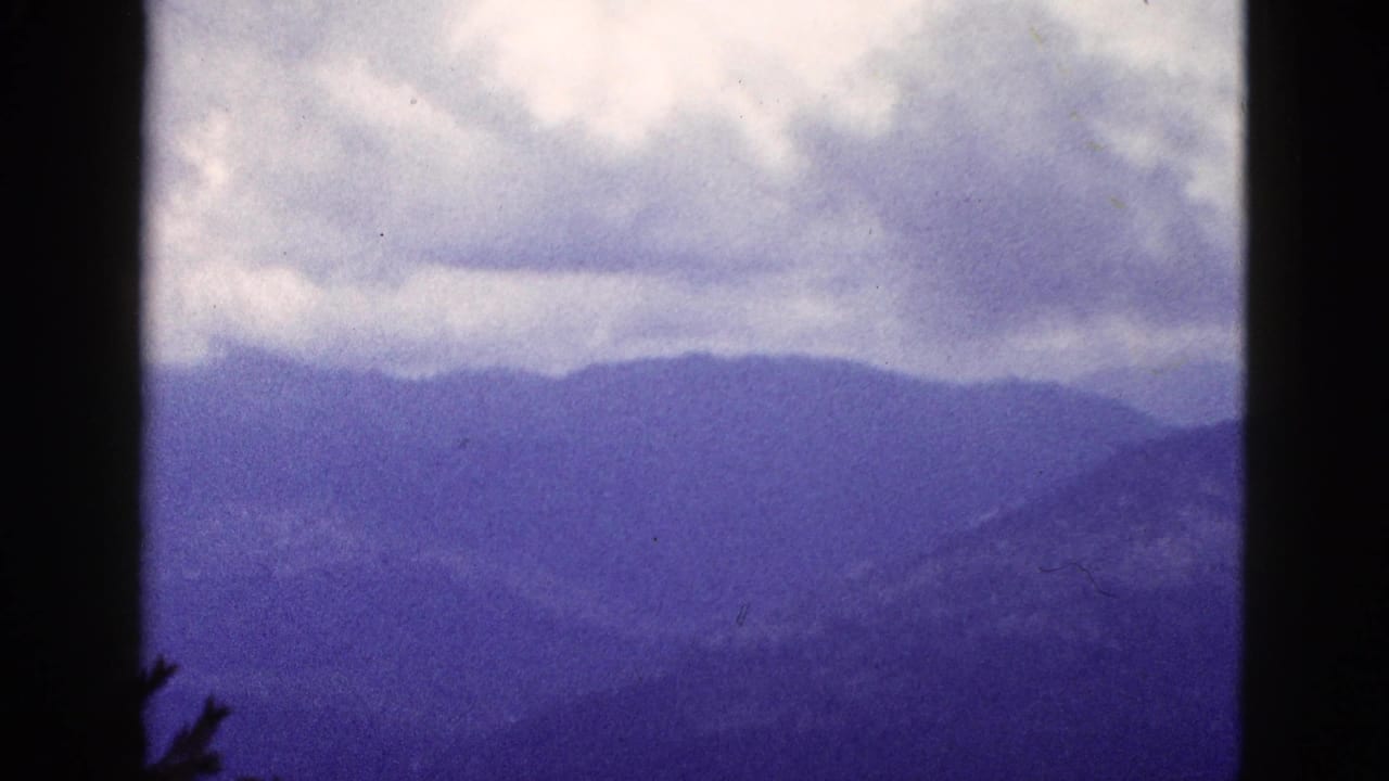 Distant mountain ridges and clouds seen through dark vertical film borders.