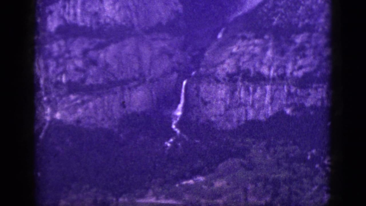 Waterfall and cliff detail in a purple, grainy frame.