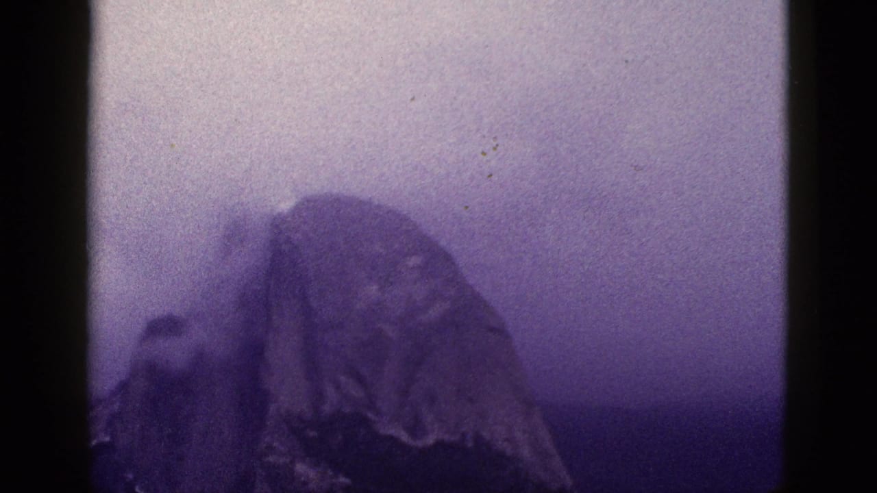 1953 8mm California footage appears to show a hazy mountain peak under a purple-toned sky, with no clear foreground faces in this frame.