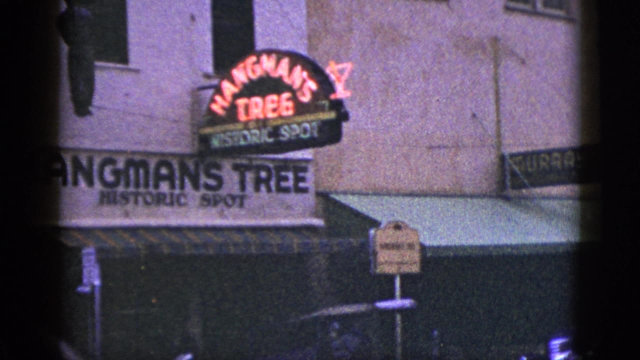 Neon Hangman's Tree sign on an old storefront with awning and sidewalk signage.
