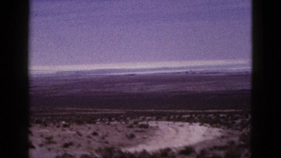 1953 California 8mm frame showing the pan across scrubby desert foreground toward a broad, hazy horizon.