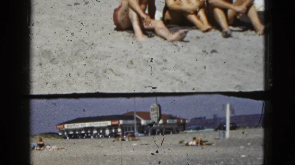 The final 1953 California beach frame widens toward the boardwalk-like background, with partial seated figures and distant beach activity.