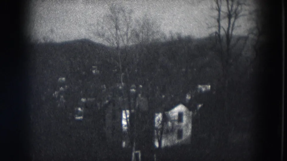 A black-and-white 8mm view of a Milwaukee-area residential hillside, with houses partly obscured by bare trees.