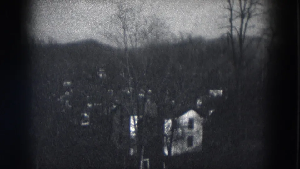 The frame shows a light-colored house and neighboring homes among leafless trees in the reported 1953 Milwaukee setting.