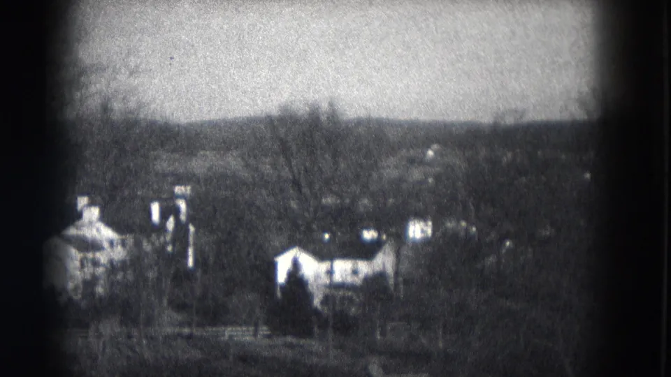 1953 Milwaukee 8mm frame with distant homes, chimneys and bare trees across a soft, grainy neighborhood view.