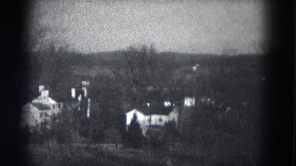 1953 Milwaukee 8mm frame showing a quiet residential hillside with houses, chimneys, bare trees and soft focus.