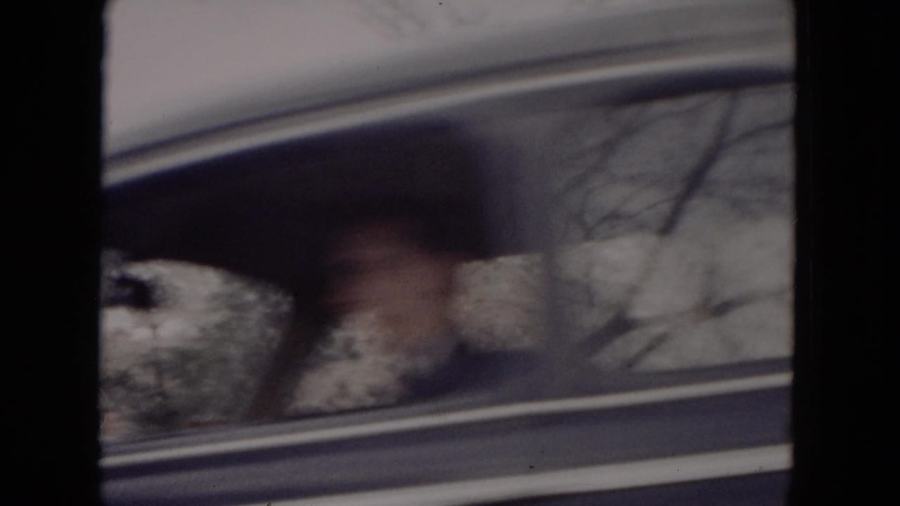 Passenger-window view in 1953 Milwaukee home-movie footage, with blurred bare trees and snow outside the car.