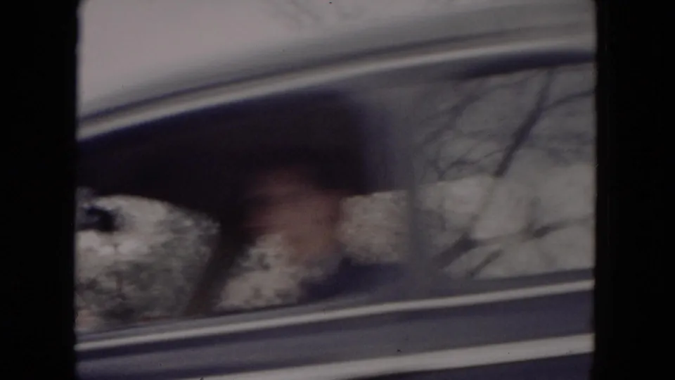 Passenger-window view in 1953 Milwaukee home-movie footage, with blurred bare trees and snow outside the car.