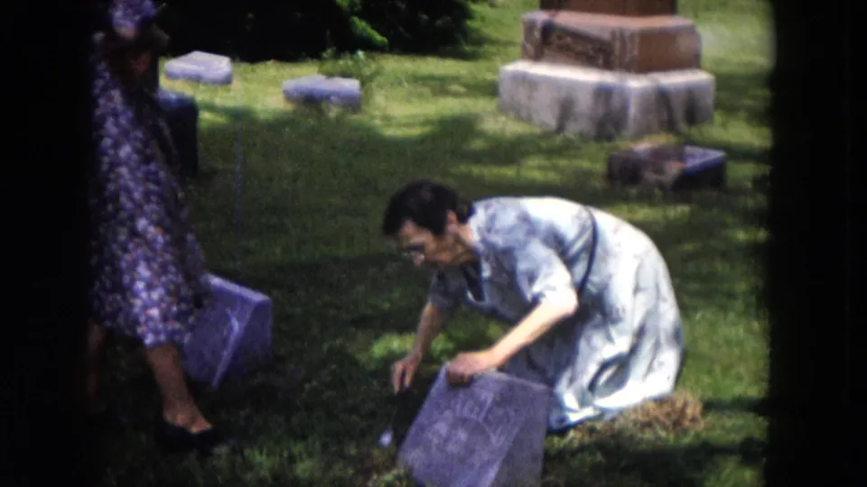A closer 1953 Milwaukee cemetery view shows a woman kneeling in the grass and reaching toward a gravestone marker.