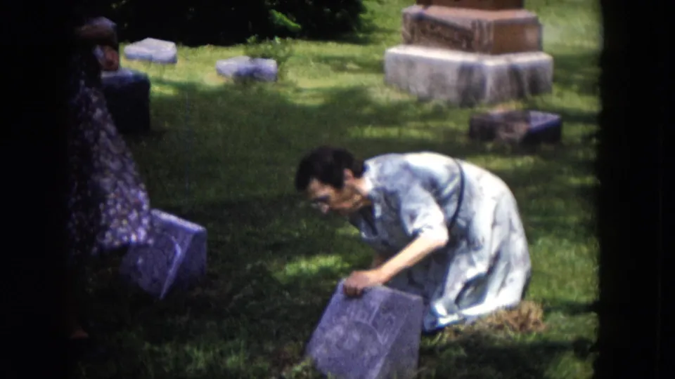 The final frame shows the kneeling woman still working near the gravestone, with monuments and small markers across the grass.