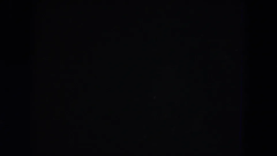 Near-black 8mm frame during the fade, with only faint grain and slight color texture visible.