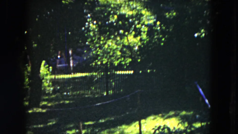 The final 1953 Milwaukee frame shows a shaded garden area with trees, a fence or railing, grass, and bright foliage in soft 8mm focus.