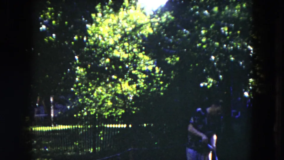 At the end of the 1953 Milwaukee clip, the man stands near the right edge as trees and fence dominate the frame.