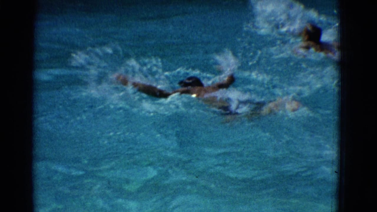 Swimmer in a dark cap doing freestyle through blue pool water.