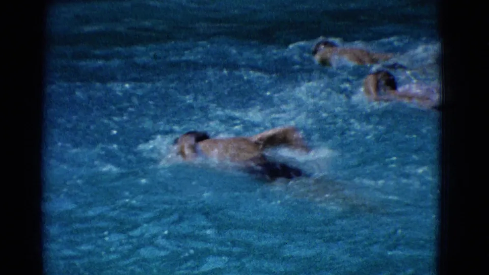 1953 Yonkers frame showing three swimmers in blue pool water, with one closest to camera and two farther back.